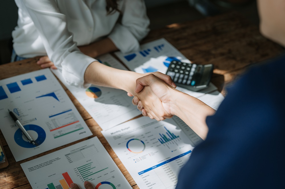 Two people shaking hands after signing a business purchase agreement